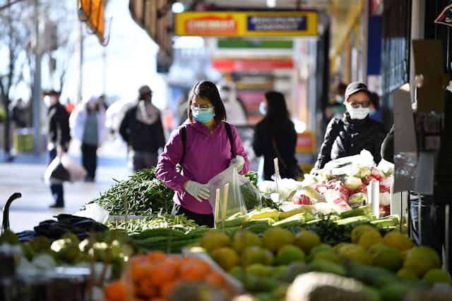 Masked woman shops for fresh produce.