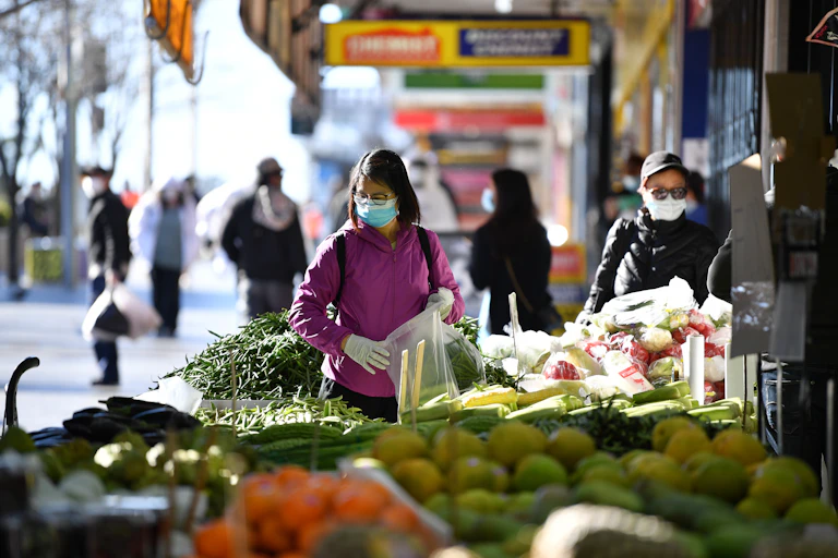 Masked woman shops for fresh produce.