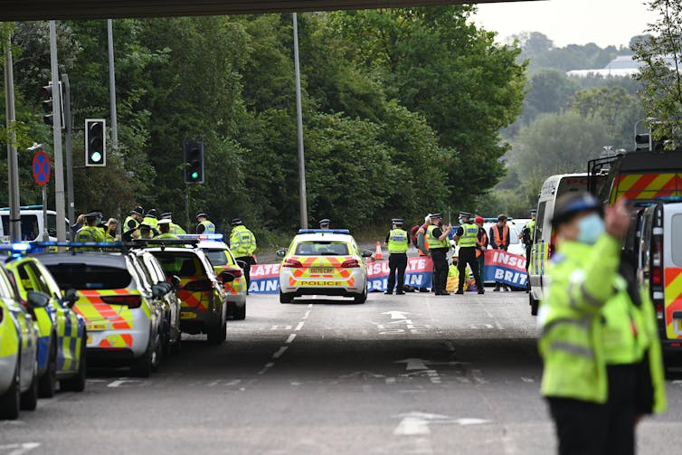 Police crowd demonstrators sat at an M25 junction.