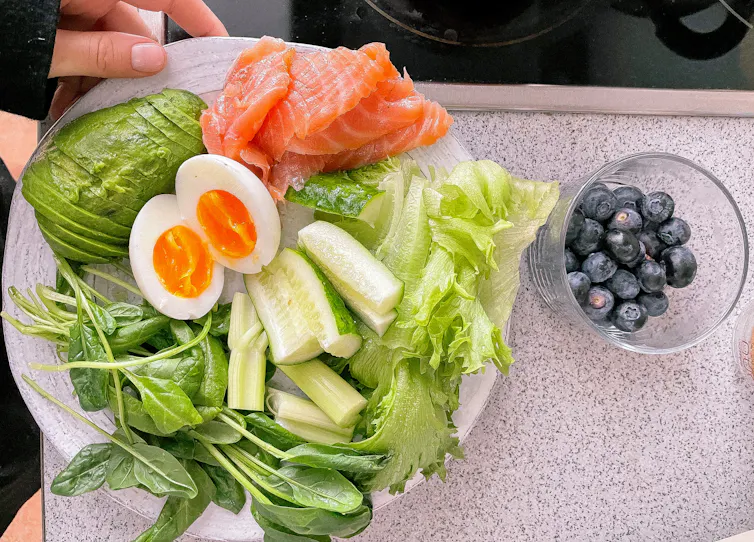 Une assiette de salade, avec œufs, avocat, saumon, etc