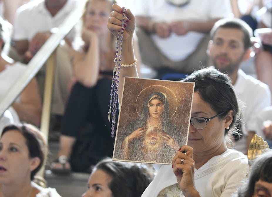 A woman holds a rosary and a picture of the Virgin Mary during a hearing challenging the constitutionality of New York State's repeal of the religious exemption to vaccination, in Albany, N.Y., Aug. 14, 2019.