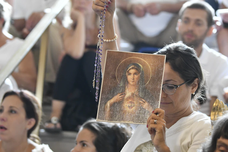 A woman holds a rosary and a picture of the Virgin Mary during a hearing challenging the constitutionality of New York State's repeal of the religious exemption to vaccination, in Albany, N.Y., Aug. 14, 2019.