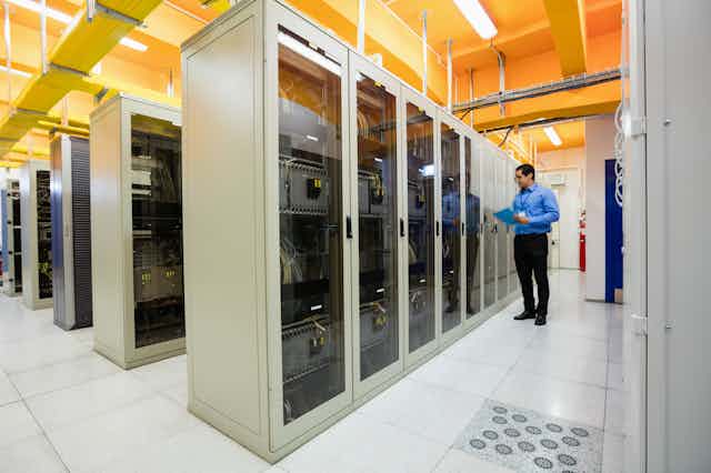 A worker inspects server cabinets which arranged in rows.