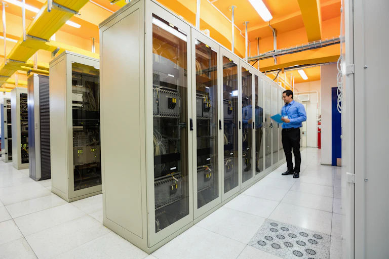 A worker inspects server cabinets which arranged in rows.