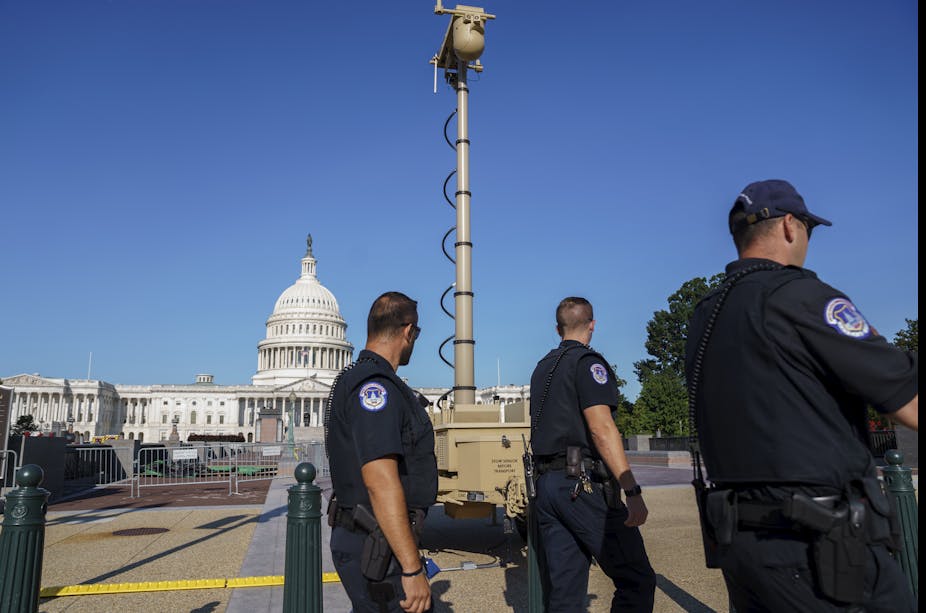 Police officers walk near a surveillance camera in front of the U.S. Capitol building