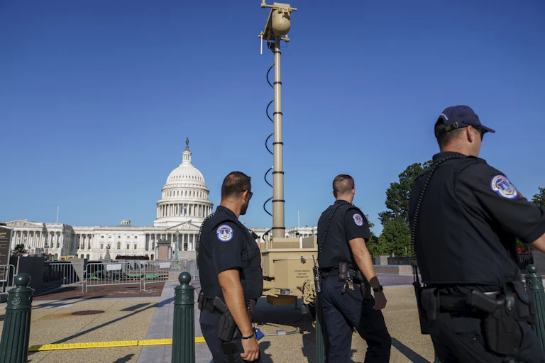 Police officers walk near a surveillance camera in front of the U.S. Capitol building
