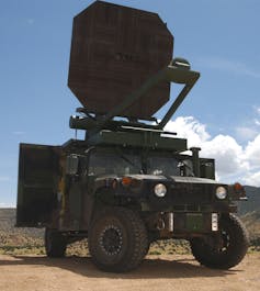 Dark green four-wheel U.S. Army truck with large octagonal antenna mounted on the roof