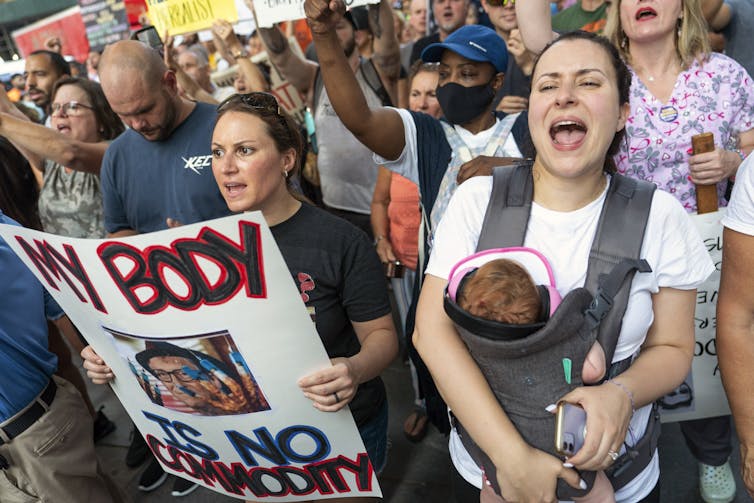 People hold signs at a demonstration against COVID-19 vaccination mandates on Aug. 25, 2021, in New York.
