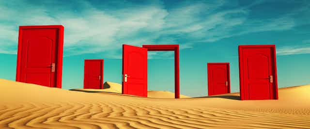 Open and shut red doors on shifting desert sands