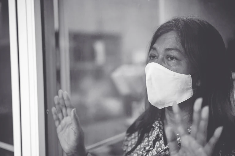 Woman looking out window with mask on