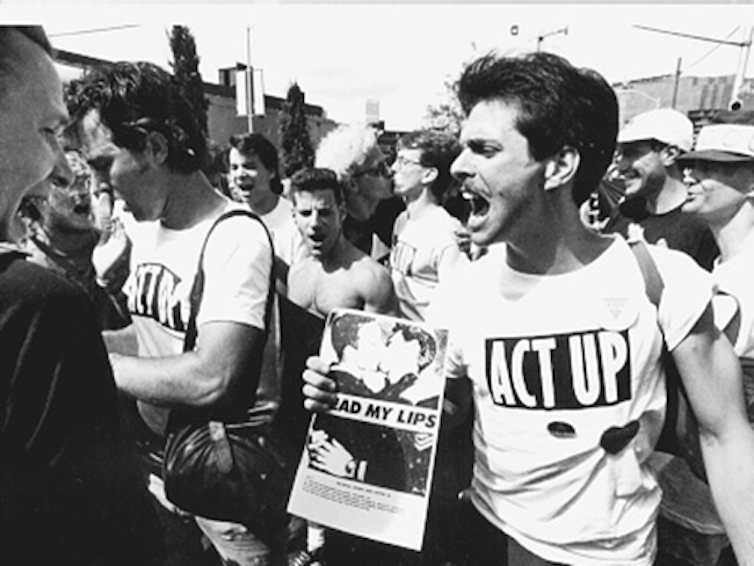 Uomini che indossano magliette ACT UP durante una protesta.