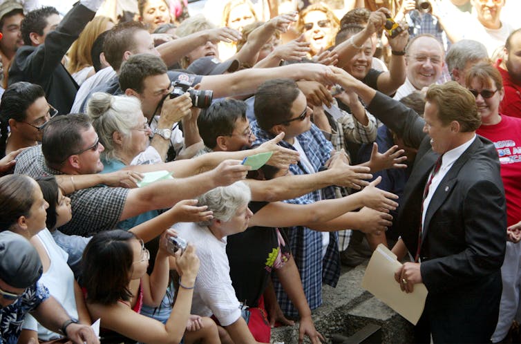 Arnold Schwarzenegger saluda a sus seguidores con los brazos extendidos durante las elecciones revocatorias de 2003 en California.