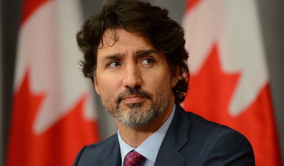 Justin Trudeau with Canadian flags behind.