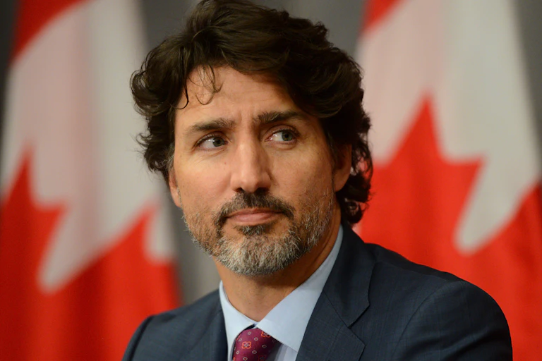 Justin Trudeau with Canadian flags behind.