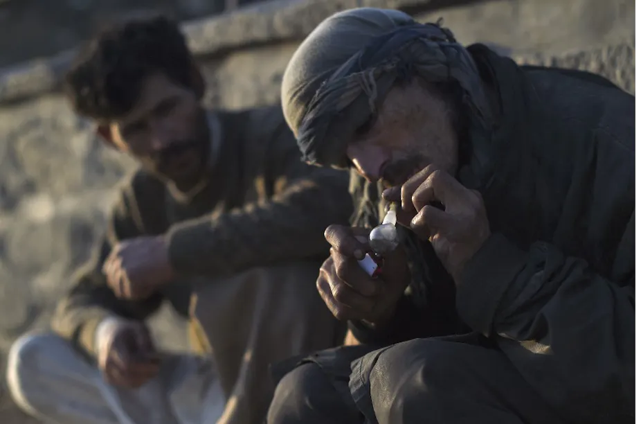 Un homme en turban fume de l'opium dans une pipe