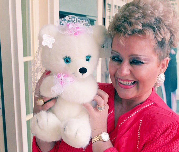 Woman smiles holding a stuffed bear.