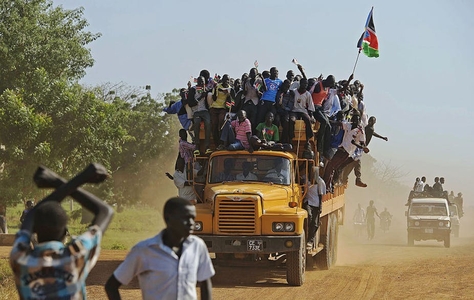 Residents hang from a bus and hold a South Sudanese flag in the disputed Abyei region of Sudan.
