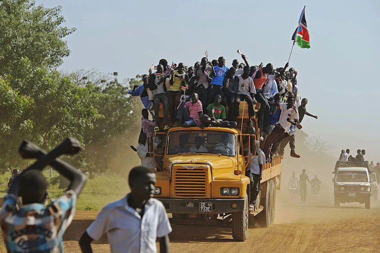 Residents hang from a bus and hold a South Sudanese flag in the disputed Abyei region of Sudan.
