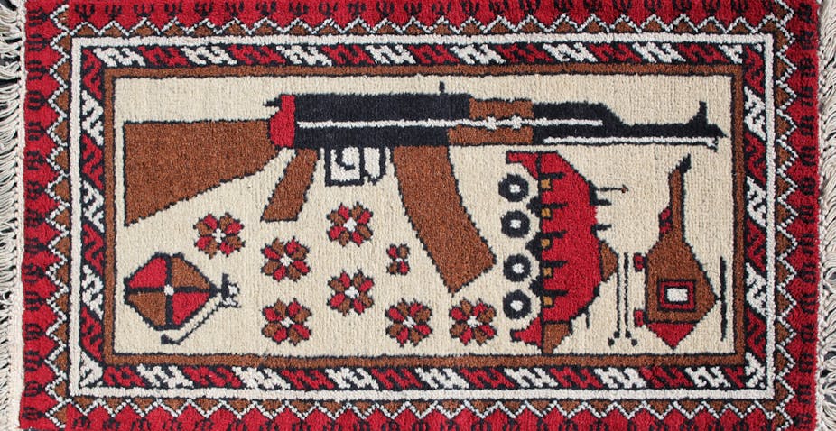 Red and white rug with AK-47, helicopter and grenade woven in.