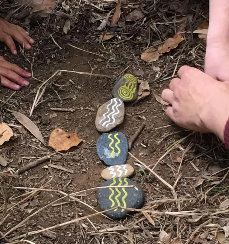 Children playing with stones painted with Indigenous symbols