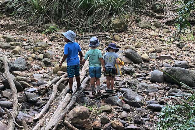 Three children playing in a dry stony creek bed