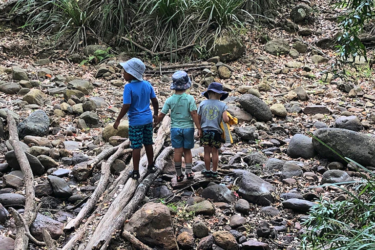 Three children playing in a dry stony creek bed