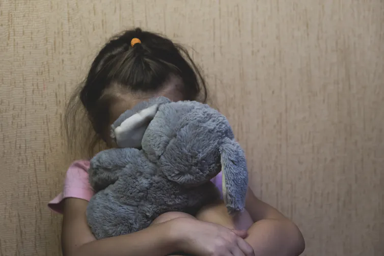 Child hides behind stuffed toy
