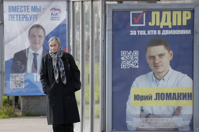 A woman walks past posters for the ruling United Russia party and the opposition Liberal Democratic Party of Russia in St Petersburg, September 2021.