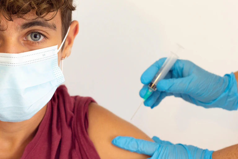 A young boy wearing a mask is vaccinated