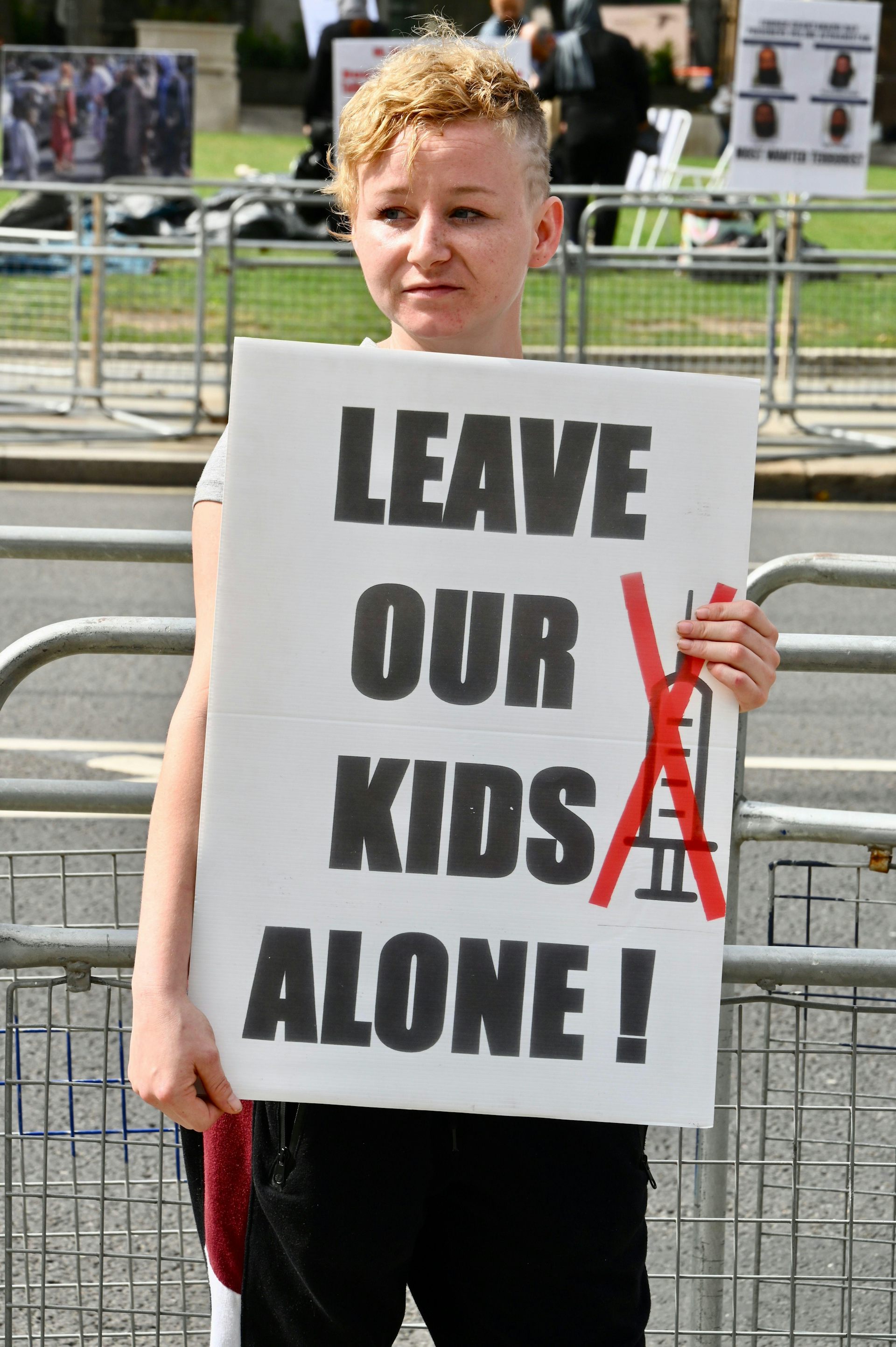 An anti-vaxx protestor in London holds up a poster saying 'Leave our kids alone'.
