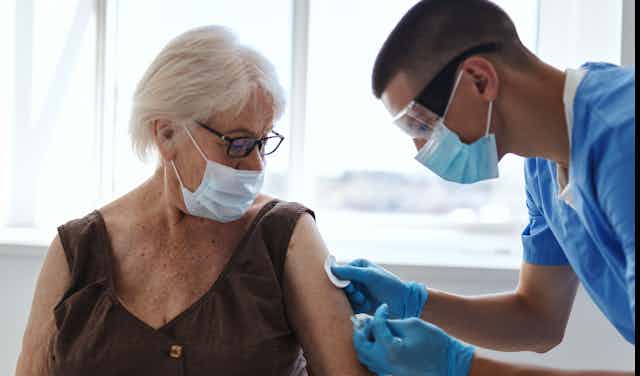 A nurse vaccinating a woman for COVID-19