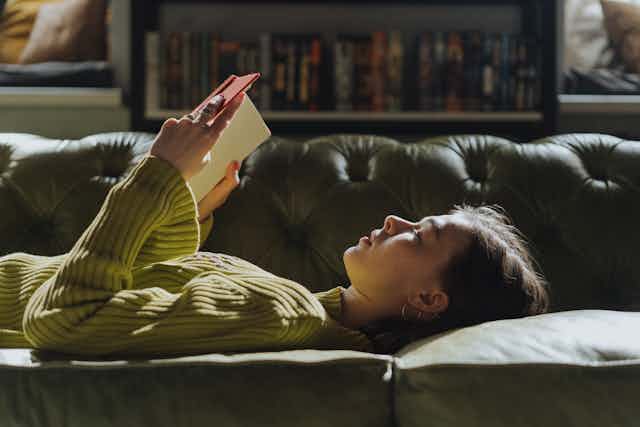 Woman lying on sofa reading