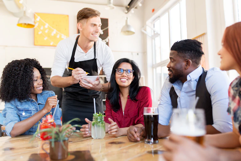 A waiter taking an order from a table of young pepople