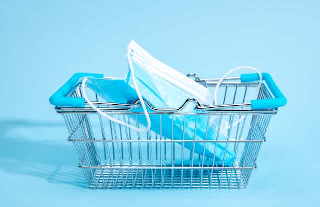A small shopping cart with a mask in it with a blue background