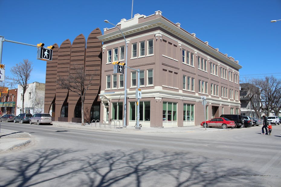 A three-storey building on a city corner seen from front and side angle.