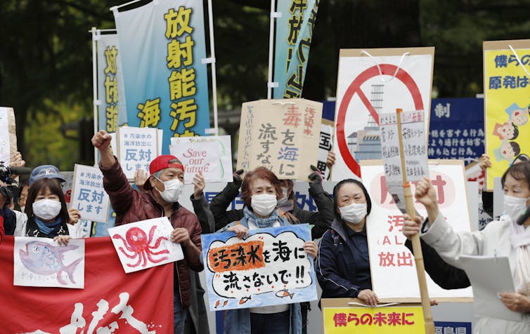 people wearing masks hold signs