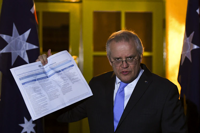 Australian prime minister Scott Morrison holding a copy of the national COVID plan.