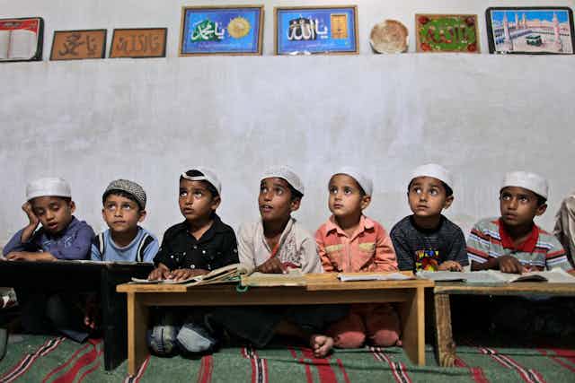 Pakistani boys listen to their teacher in a madrassa.