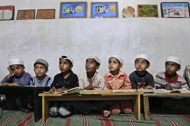 Pakistani boys listen to their teacher in a madrassa.