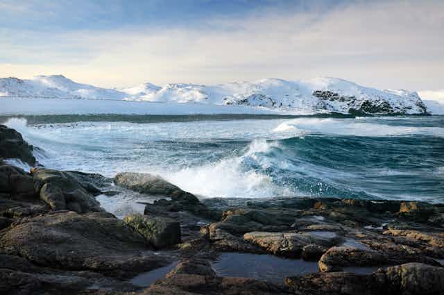 Snow covered Arctic mountains and ocean.