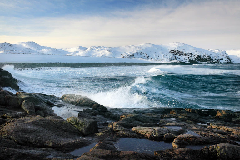 Snow covered Arctic mountains and ocean.