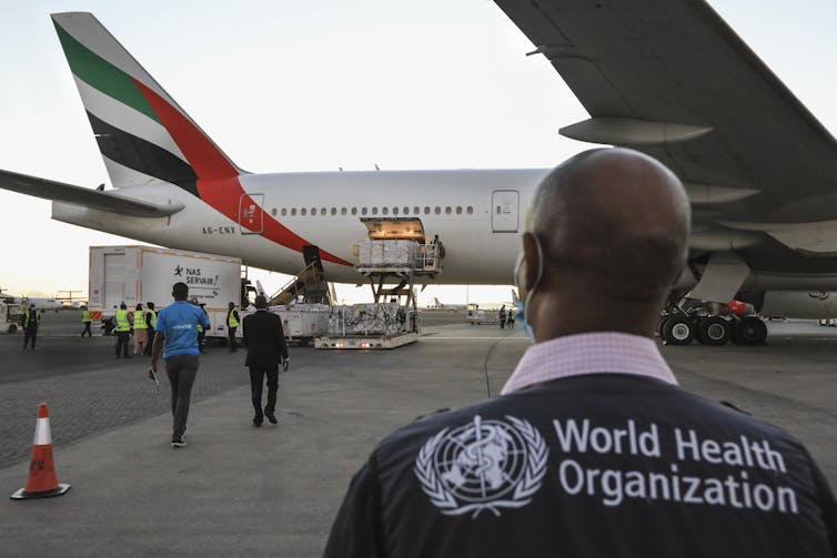 A World Health Organization official watching Covax doses being unloaded from a plane in Kenya