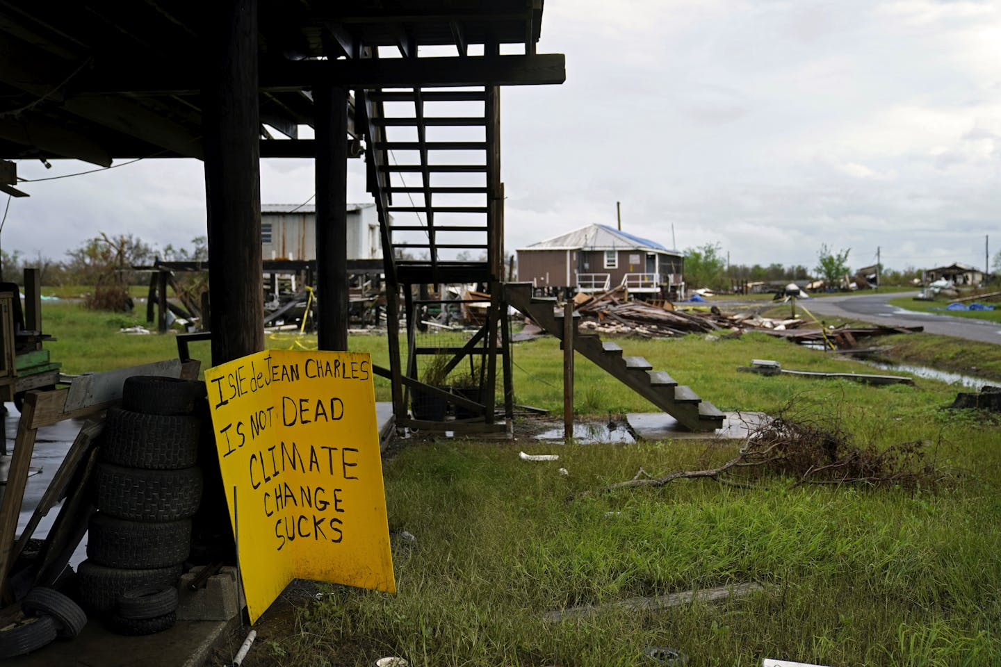 Severely damaged homes and a sign that reads: 'Isle de Jean Charles is not dead. Climate change sucks.'