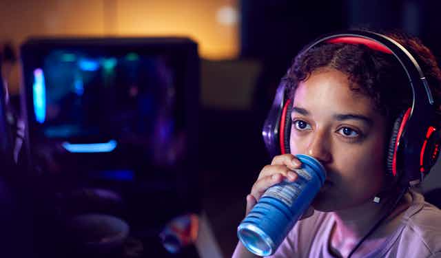 teen girl consumes an energy drink while playing video games