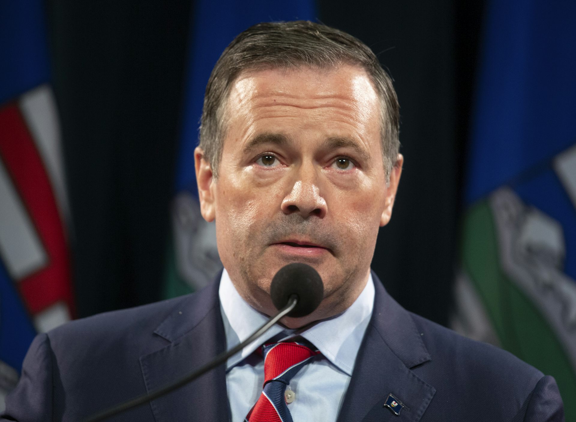 Jason Kenney speaks into a microphone.