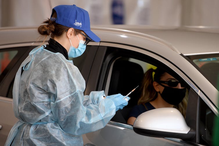 Nurse at car window with syringe