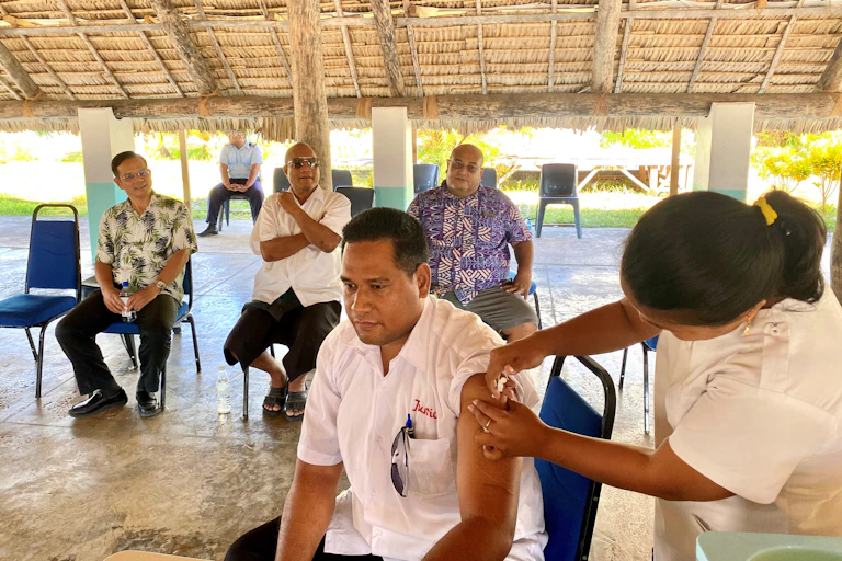 Man being vaccinated by nurse while others watch