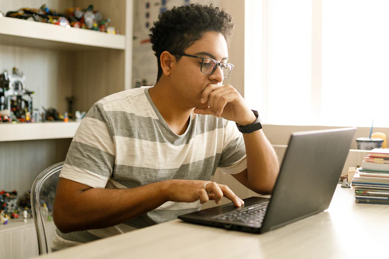teenage boy using a laptop in his room