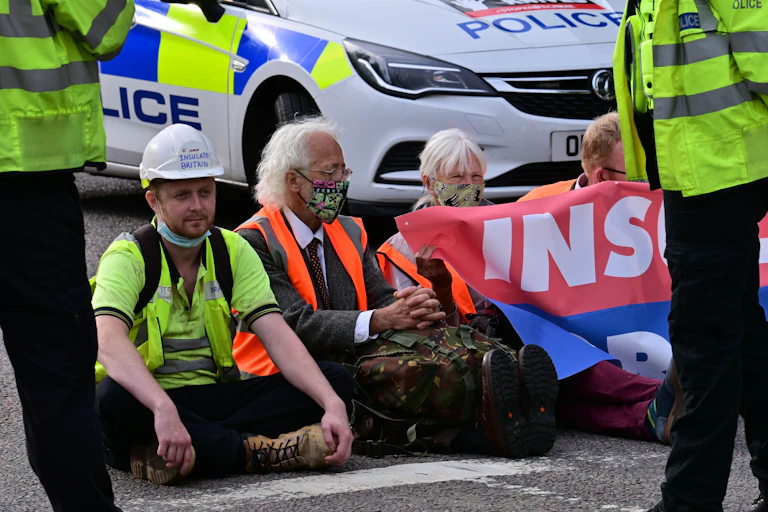 Protesters sit on tarmac surrounded by police.