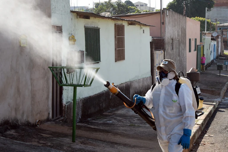 A worker in protective clothing sprays pesticides in Gama, Brazil, 2016.